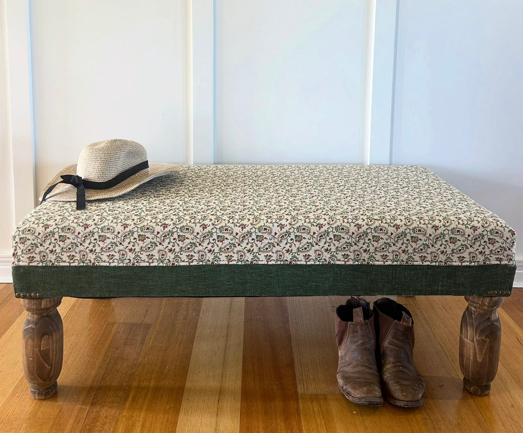 Floral upholstered bench with a deep green border and turned timber legs